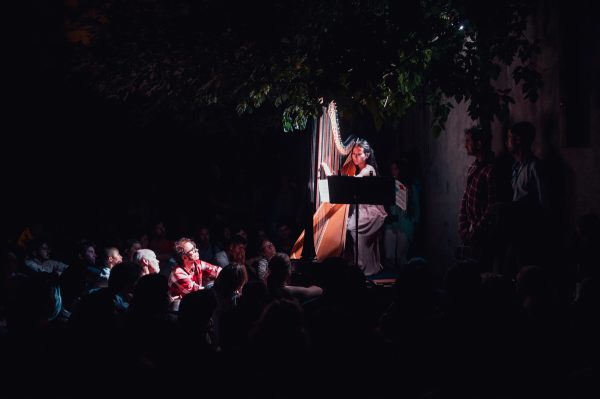 a sunken courtyard amongst some industrial buildings on Morrow Ave. We all descended a staircase into the space to find harpist Emily Belvedere beautifully lit and waiting for us on a makeshift stage of shipping palettes. She performed a contemporary piece by French-Canadian composer Caroline Lizotte titled Suite Galactique