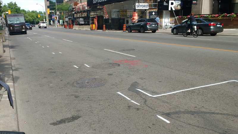 Markings on pavement indicating bike lane and parking, Bloor East