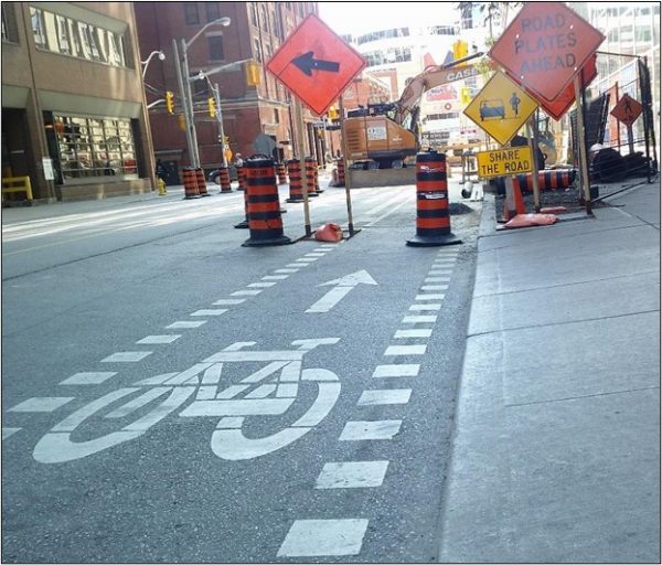 Construction zone with sign indicating cyclists share the road with vehicles