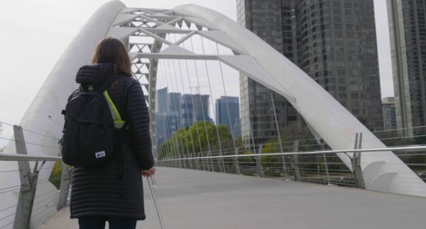 Woman with cane standing on wide path of Humber pedestrian and cycling bridge