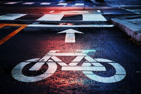 Macro of white bike lane markings on a street at night near a crosswalk.